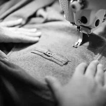 couturière qui cout la boutonniere d'un pull en laine