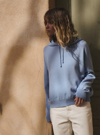 pull claude bleu aster sweat femme tricot léger capuche style moderne contre un mur